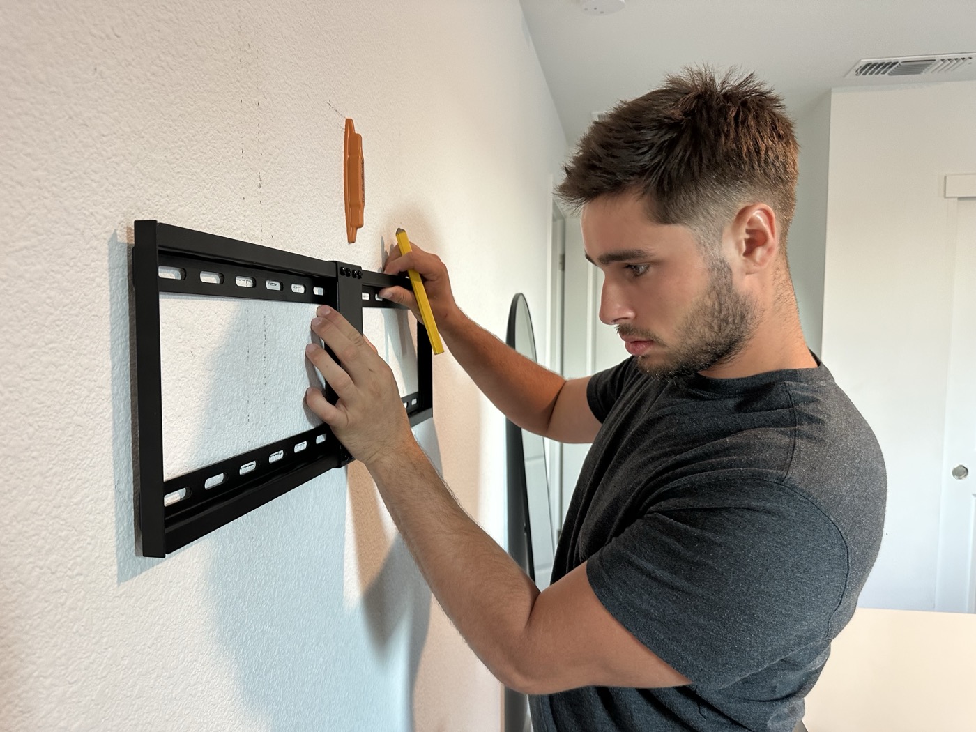 Skyler, owner of Sting Solutions, mounting a TV on the job